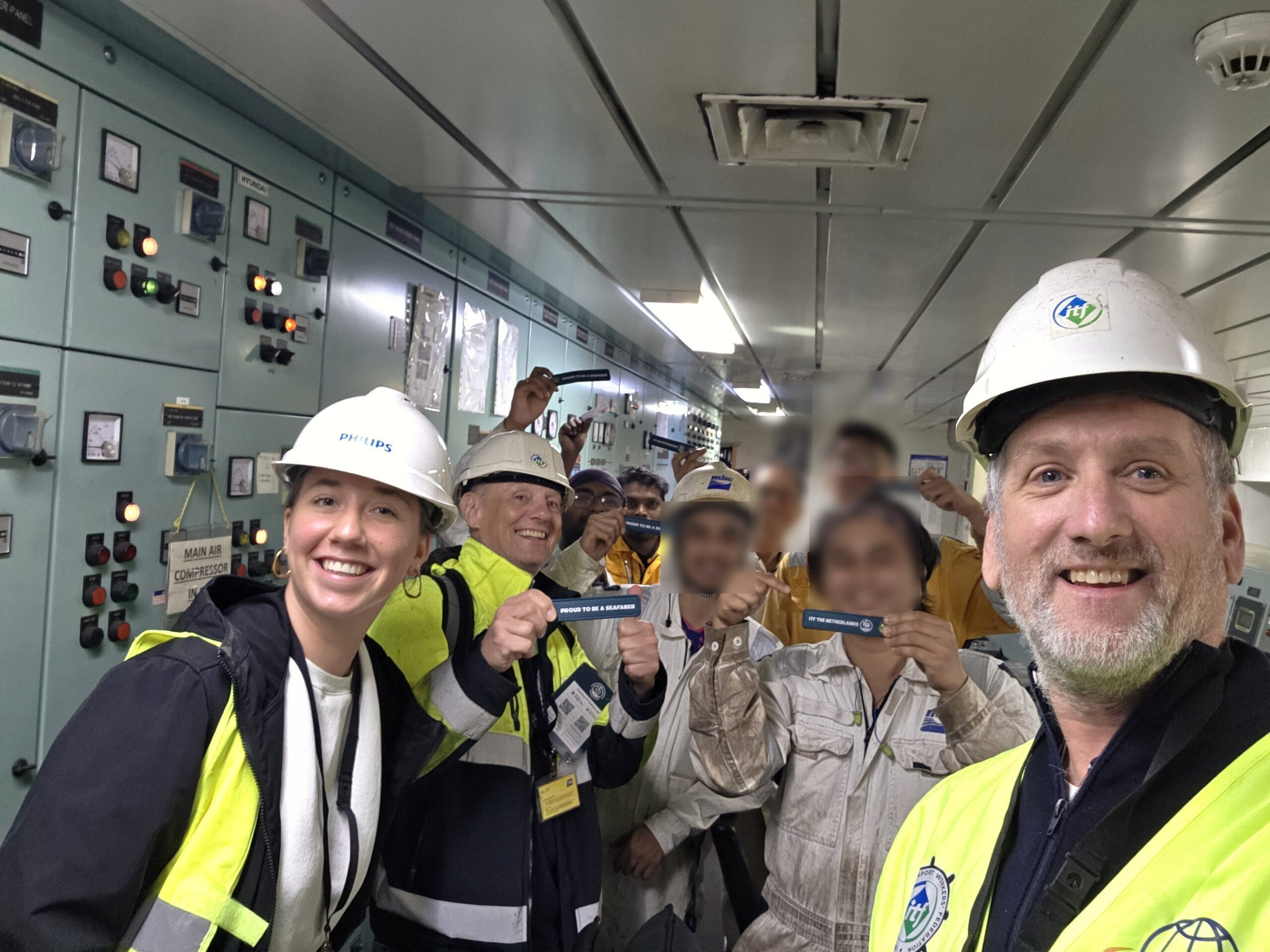 Remko Schats with ITF colleagues and seafarers in a ship engine room, holding Proud to be a Seafarer bands